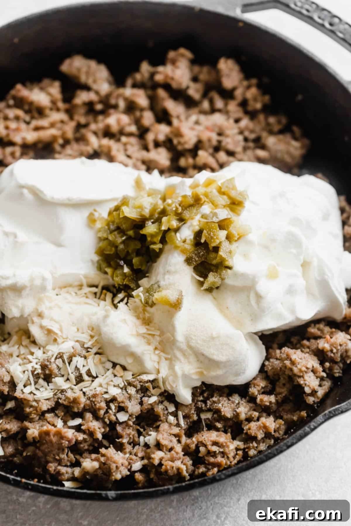 Κρεμώδες Ντιπ Λουκάνικου 4 Ντιπ λουκάνικου Jimmy Dean σε τηγάνι με τυρί κρέμα και ψιλοκομμένους χαλαπένιος από πάνω.