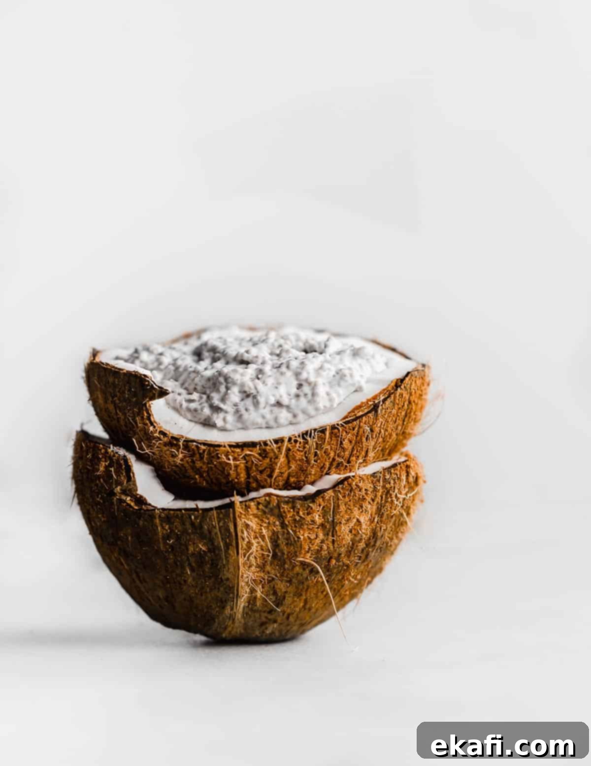 Tropical Chia Pudding Bliss 2 A raw coconut filled with Overnight Coconut Chia Pudding against a white background.