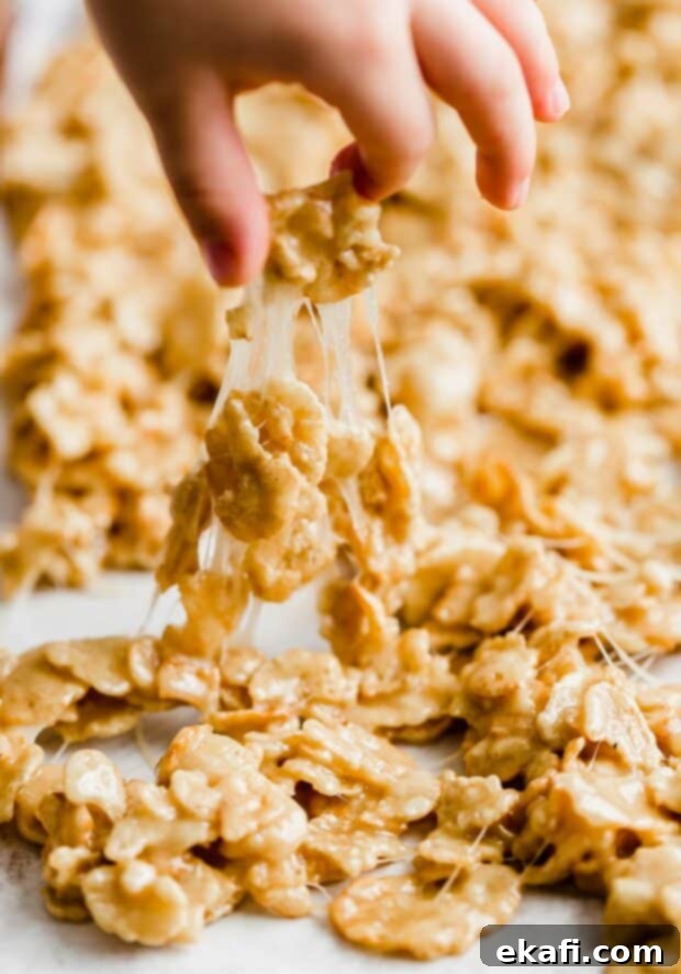 Special K Crunch Bites 9 A hand pulling up a gooey piece of marshmallow coated Special K cereal, showcasing its tempting stickiness and rich color.
