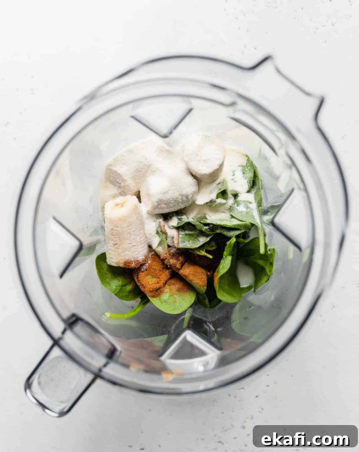 Πράσινο Πρωτεϊνούχο Smoothie 4 Φωτογραφία από πάνω ενός μπλέντερ γεμάτου με σπανάκι, μπανάνες και κανέλα σε σκόνη.