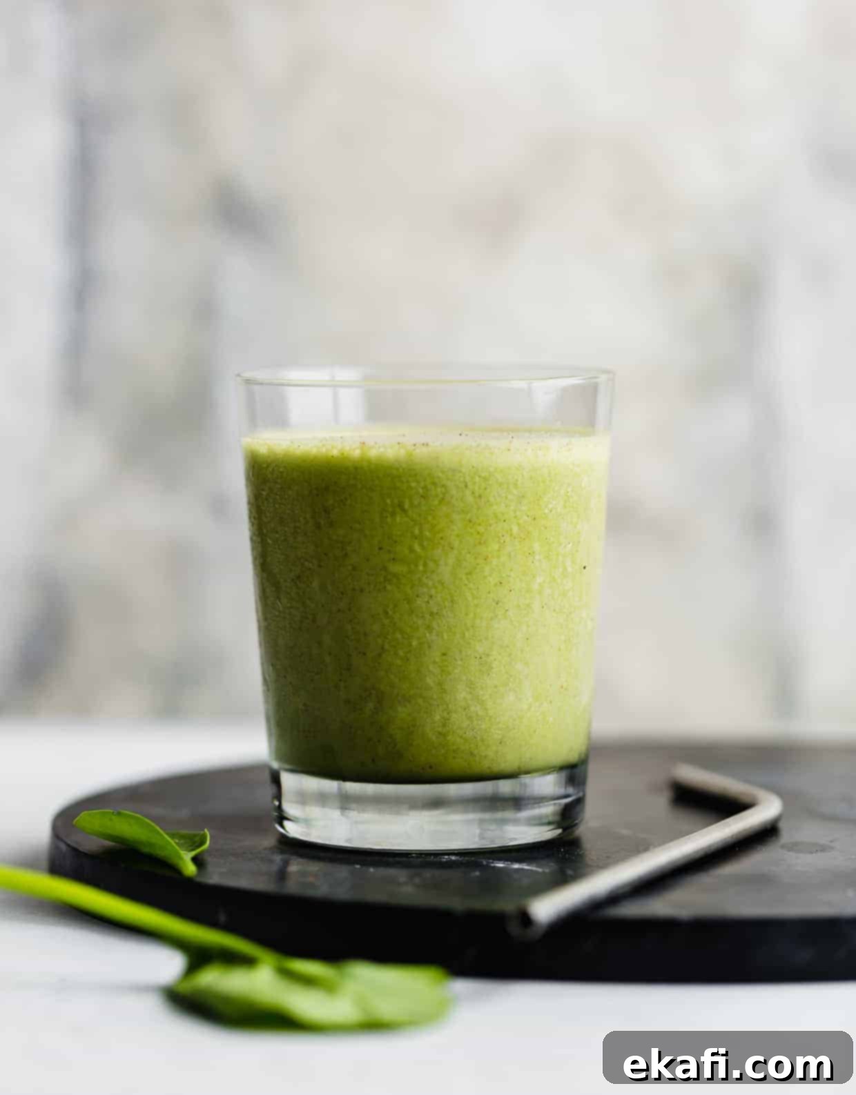 Πράσινο Πρωτεϊνούχο Smoothie 7 Ένα πράσινο smoothie σε ένα φλιτζάνι με φύλλα σπανάκι στο προσκήνιο.