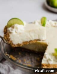 Velvety Key Lime Indulgence 8 A slice of Key Lime Pie with sour cream on a graham cracker crust balancing on a serving knife.