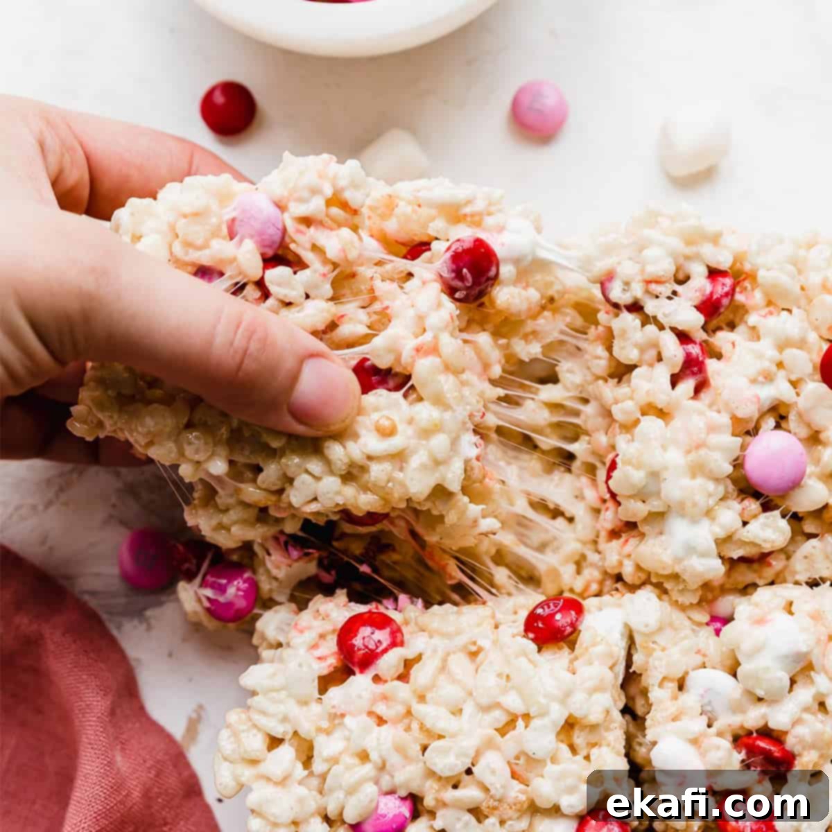 Colorful M and M Rice Krispie Bars 8 A hand pulling a square of M&M Rice Krispie treats.
