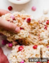 Colorful M and M Rice Krispie Bars 9 A hand pulling a square of M&M Rice Krispie treats.