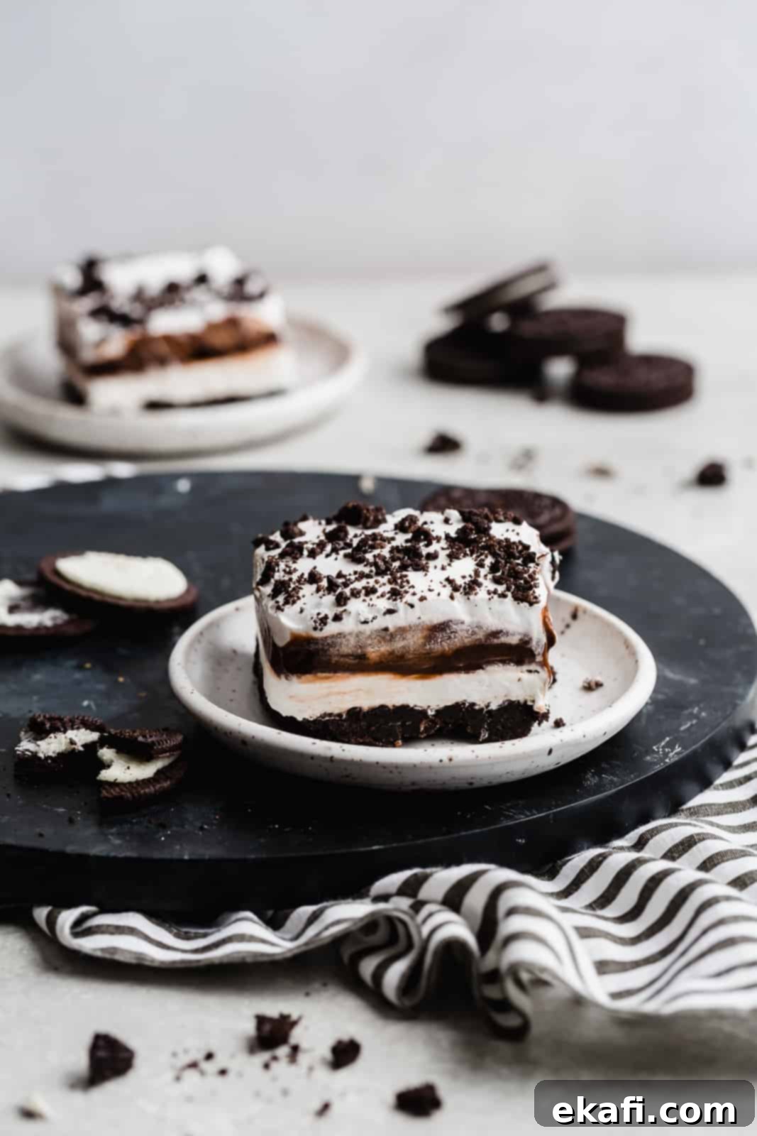 Effortless Oreo Magic 2 An Oreo layered dessert on a white plate with crushed Oreos to the side.
