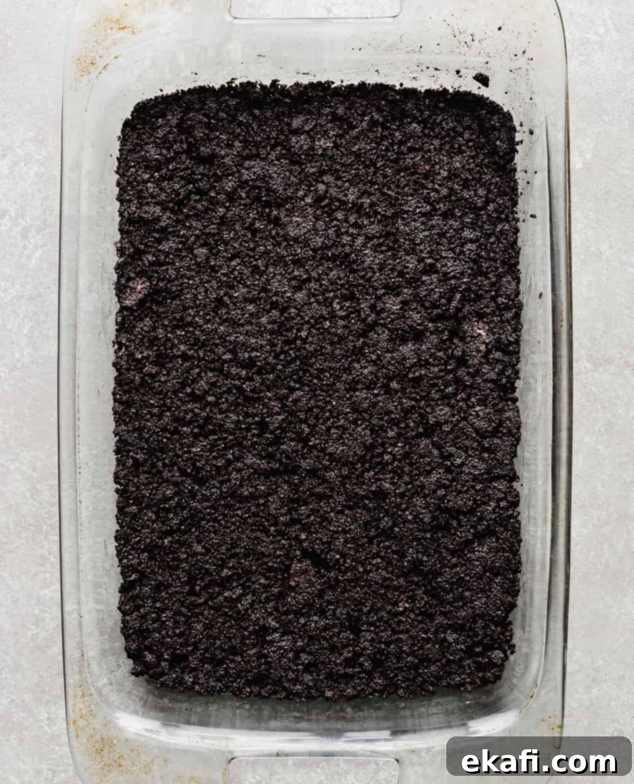 Effortless Oreo Magic 5 An oreo crust filling the bottom of a 13 inch by 9 inch pan.