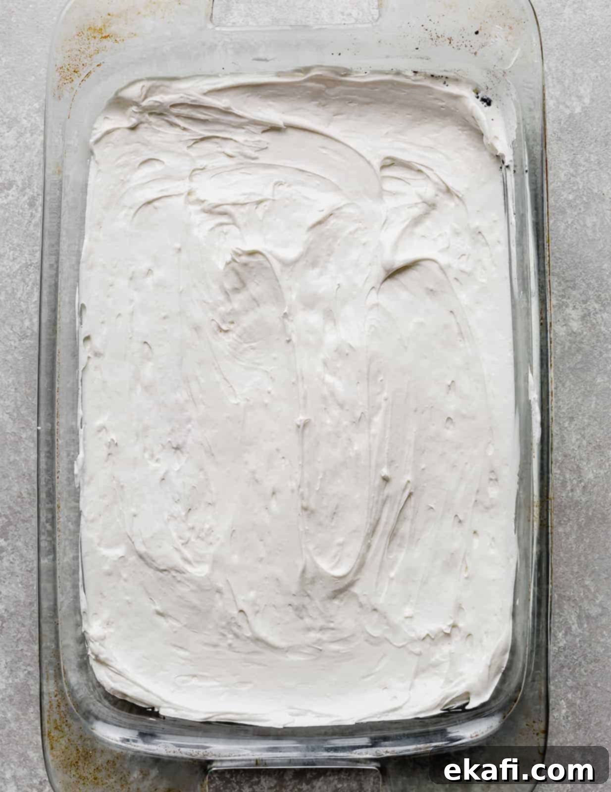 Effortless Oreo Magic 6 A 9 inch by 13 inch pan with a layer of cream cheese filling spread along the bottom.
