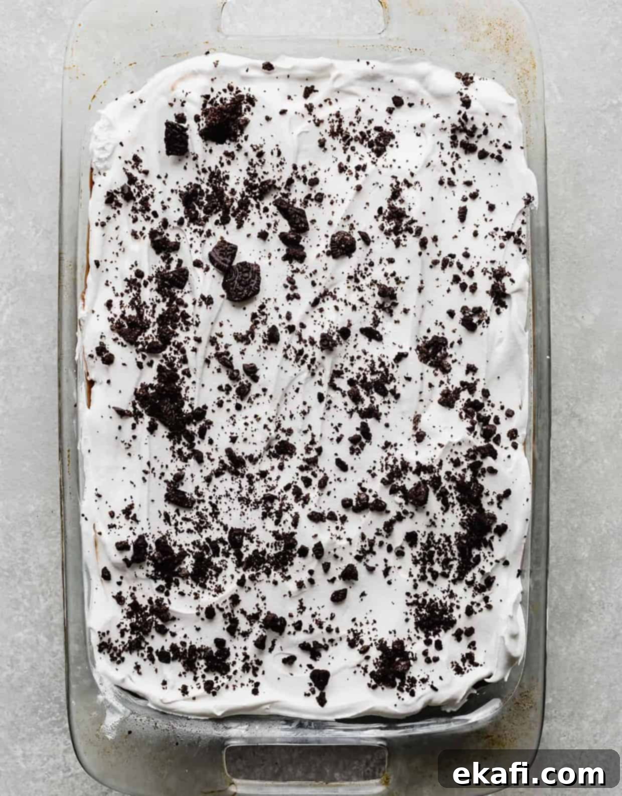 Effortless Oreo Magic 8 Overhead photo of a casserole dish full of an Oreo layer dessert topped with white whipped cream and crushed Oreos.