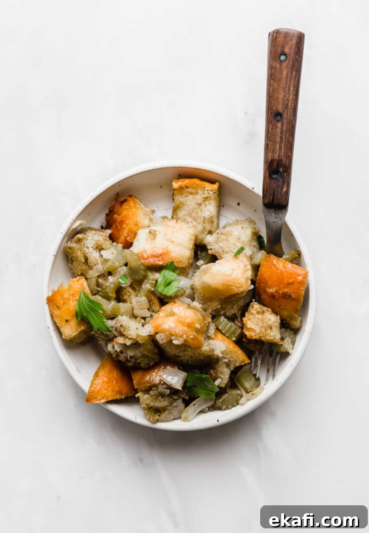 The Ultimate Thanksgiving Stuffing 9 A serving of Thanksgiving Stuffing on a white plate on a white background.