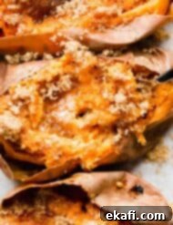 Easy Baked Sweet Potato 8 A close up of a Baked Sweet Potato topped with butter and brown sugar with a fork mixing the potato flesh.