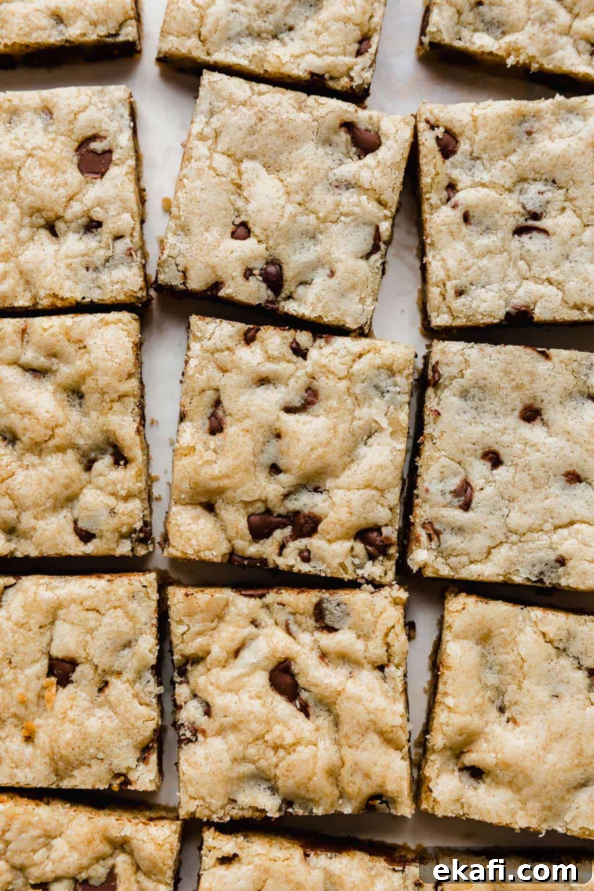 Decadent Chocolate Chip Cookie Bars 2 Chewy Chocolate Chip Cookie Bars lined up on a white background, showcasing their soft, golden-brown edges and molten chocolate chips.