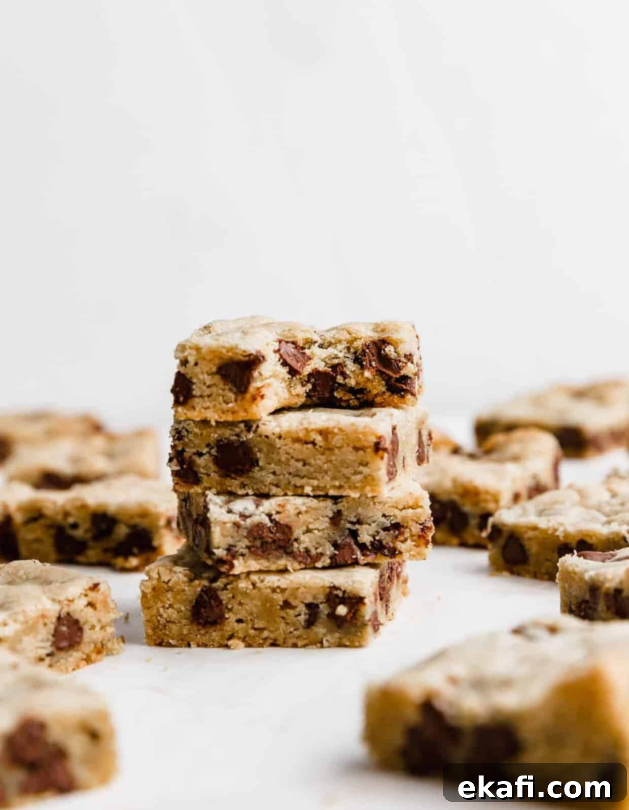 Decadent Chocolate Chip Cookie Bars 11 A stack of 4 perfectly cut, chewy Chocolate Chip Cookie Bars against a clean white background, highlighting their delicious texture.