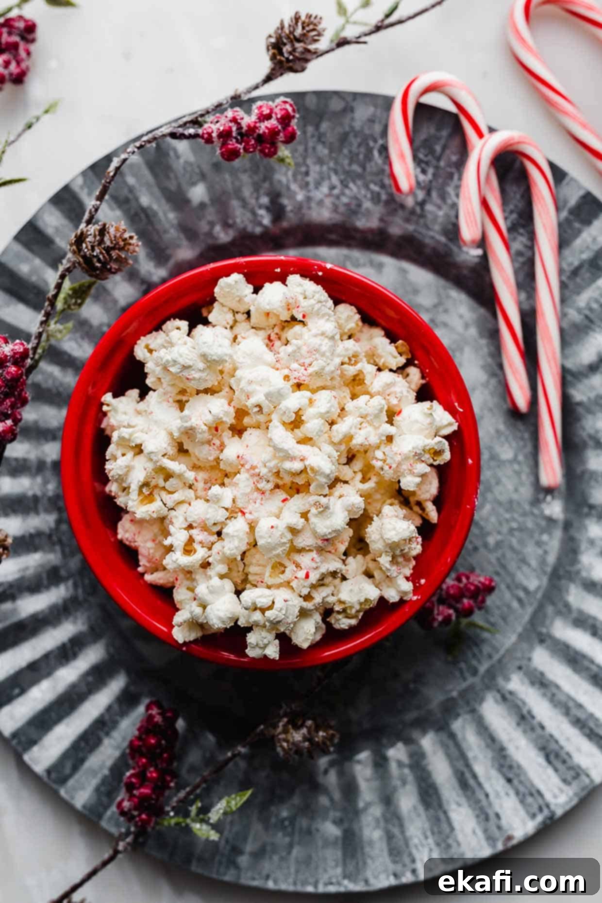 Ζαχαρομπαστουνένιο Ποπ κορν 6 Candy Cane Popcorn σε κόκκινο μπολ πάνω σε μια μεγάλη γκρι μεταλλική πιατέλα.