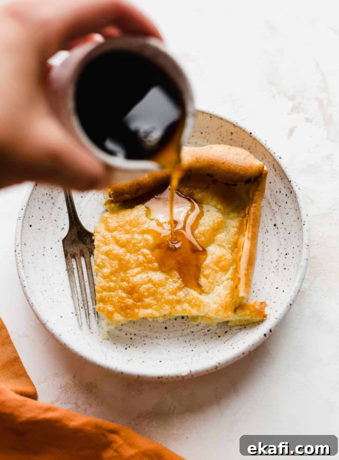 Brown maple syrup being poured overtop a German Pancake.