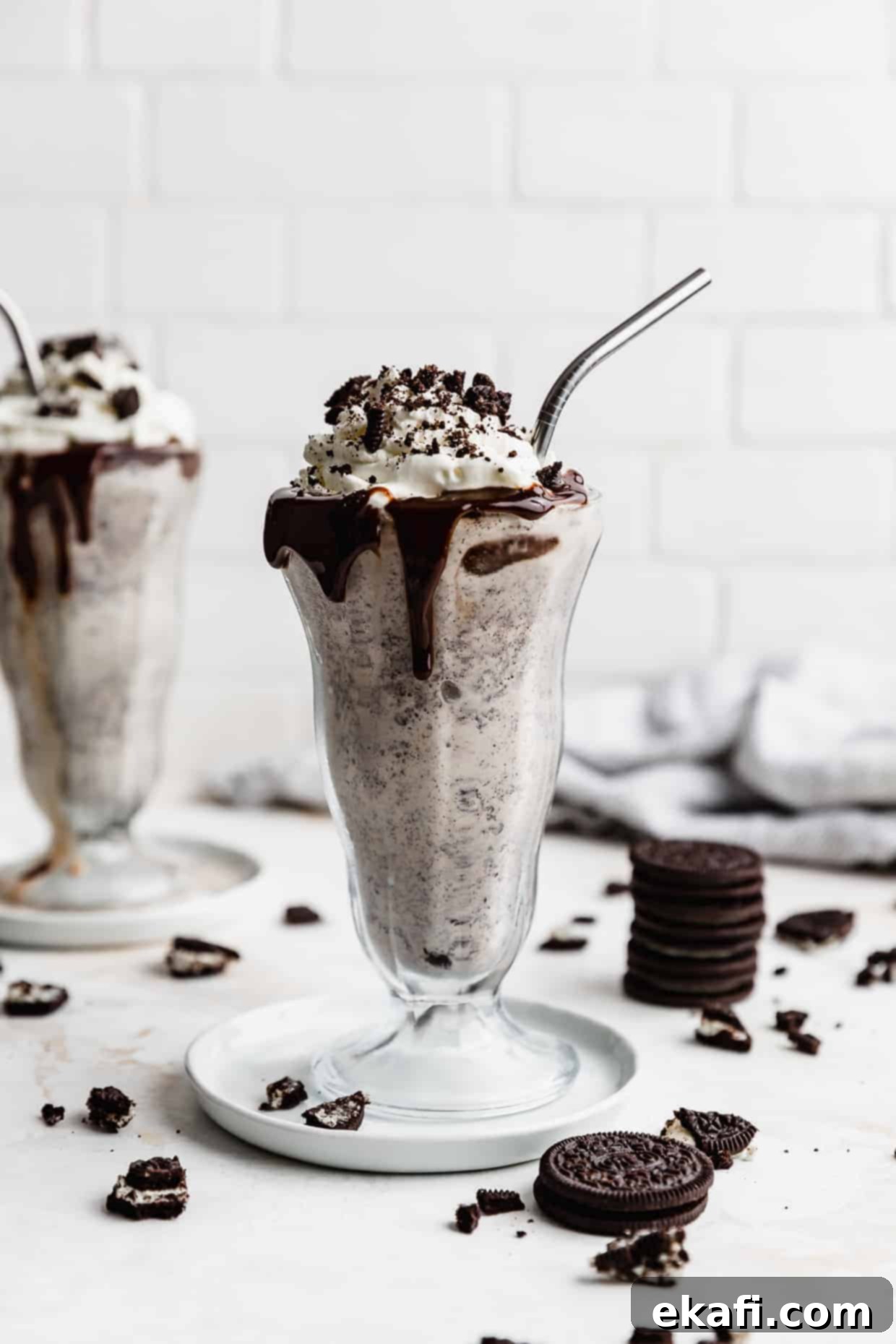 Ultimate Oreo Indulgence 2 Two tall glasses full of Oreo milkshake topped with whipped cream and crushed Oreos.