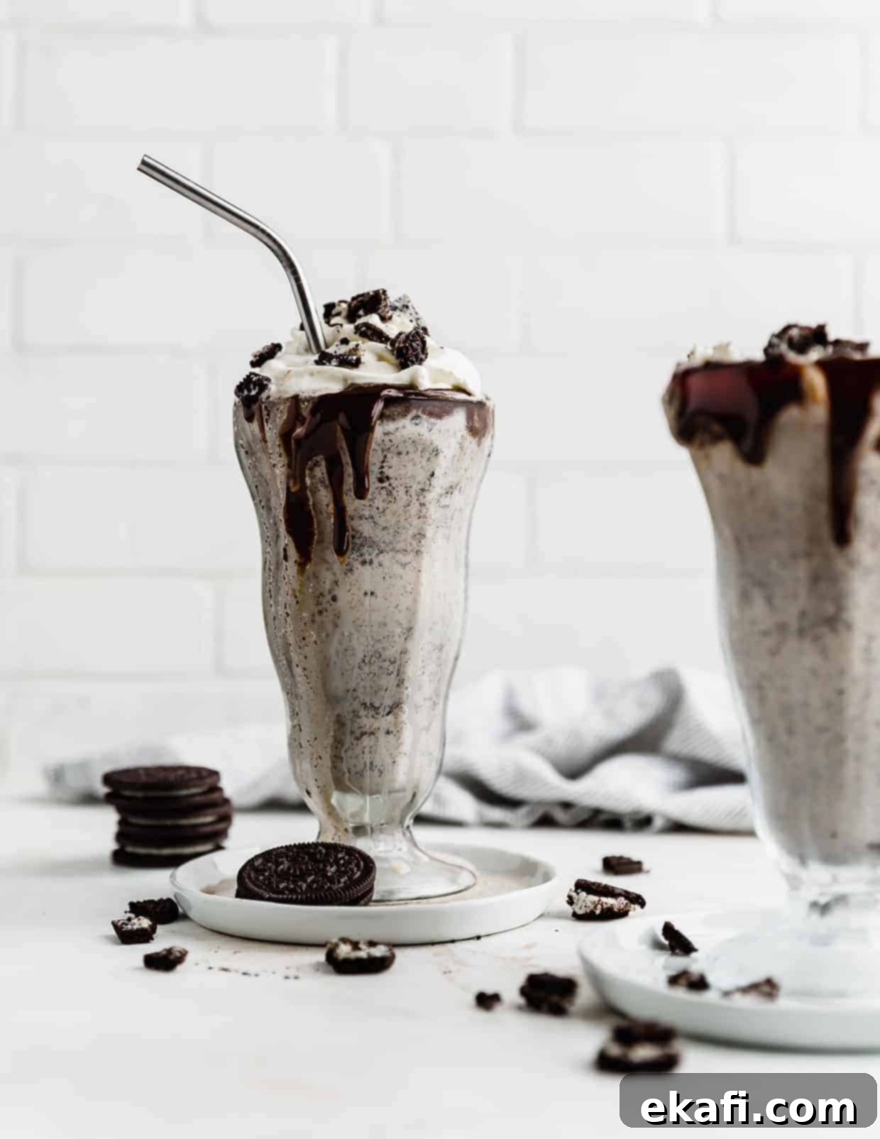 Ultimate Oreo Indulgence 6 An oreo milkshake in a large glass cup, against a white brick background.