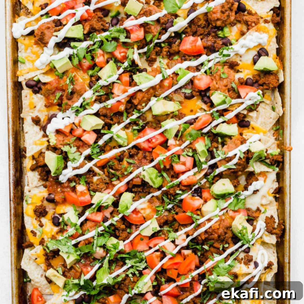 Gridiron Grub 11 Sheet pan nachos topped with beef, sour cream, tomatoes, cilantro, and avocado.