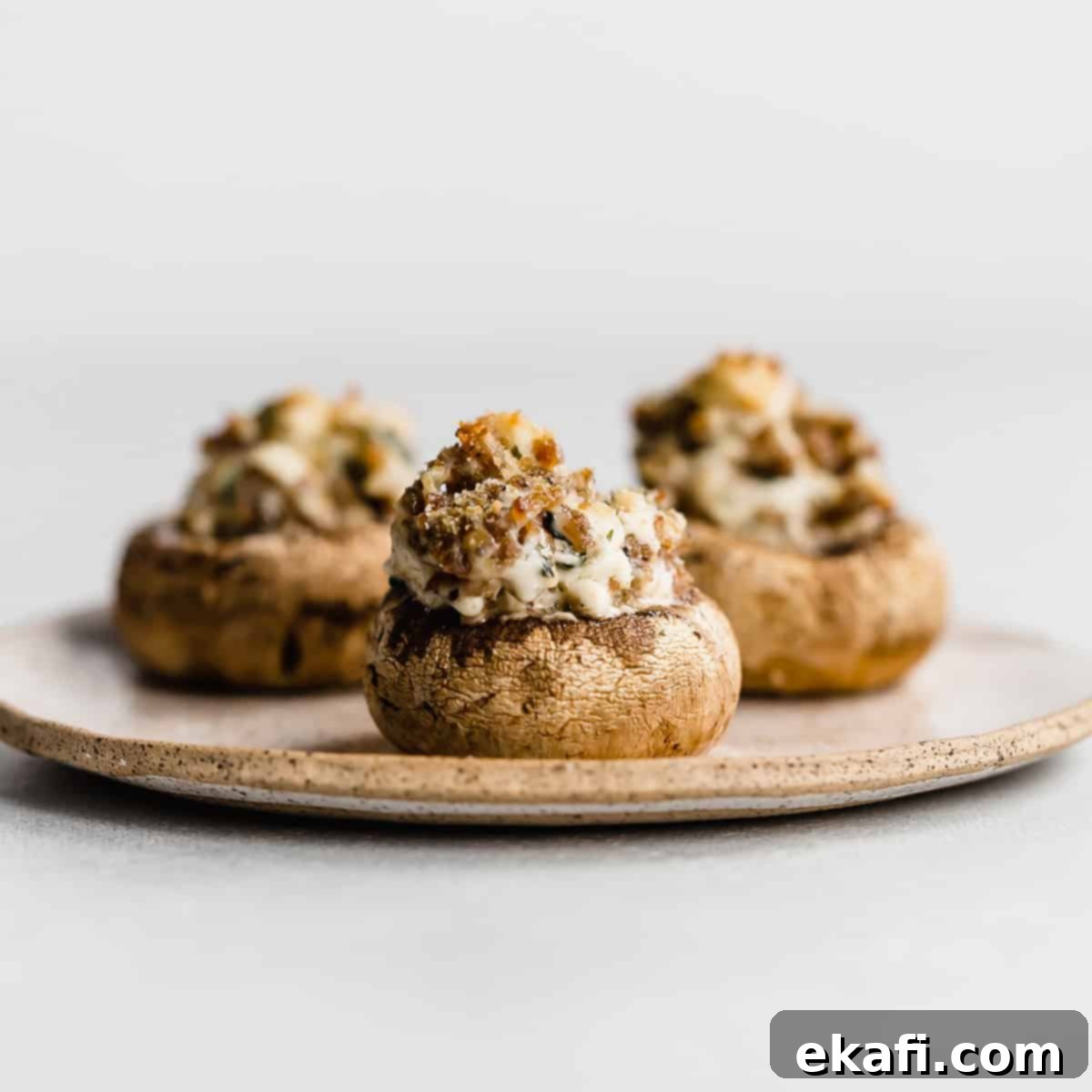 Gridiron Grub 13 Three Italian Sausage Stuffed Mushrooms on a tan plate against white background.