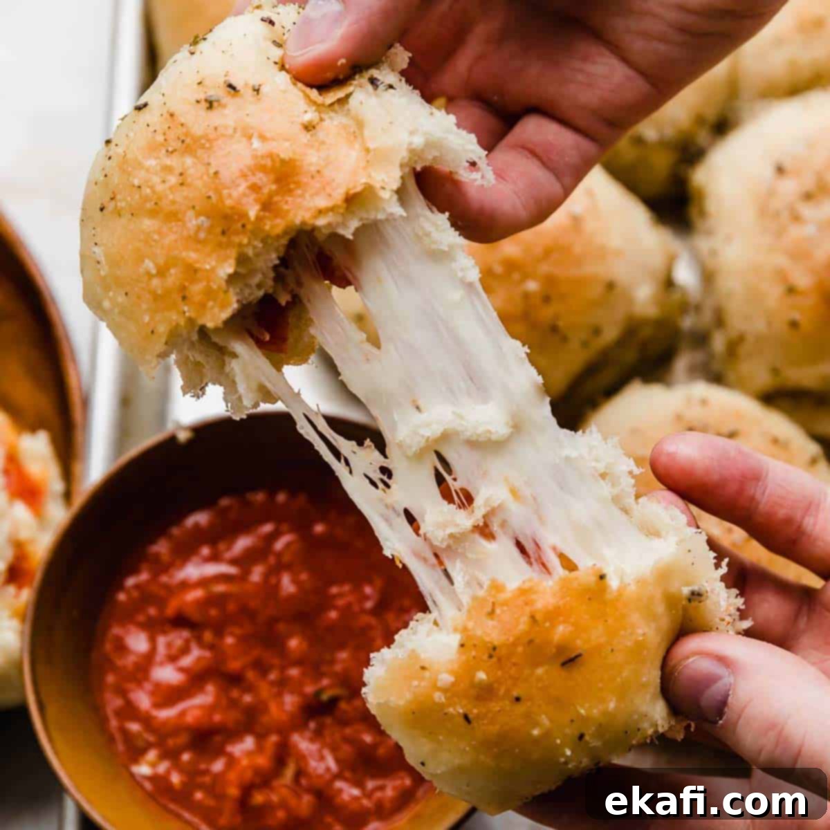 Gridiron Grub 17 Two hands pulling a pizza roll apart showing the stretchy mozzarella cheese and pepperoni inside.