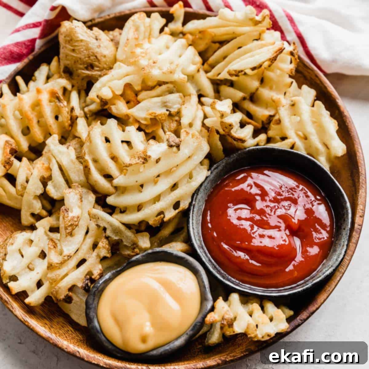 Gridiron Grub 18 Waffle fries on a brown plate with bowls of ketchup and chick fil a sauce beside them.