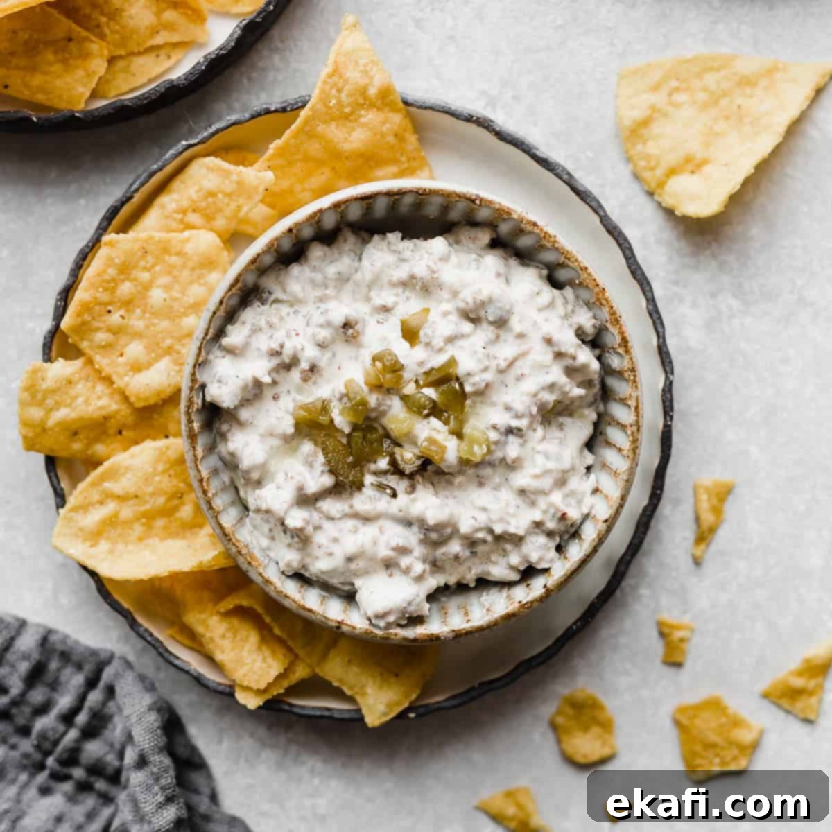 Gridiron Grub 3 Cream Cheese Sausage Dip in a white bowl topped with chopped jalapeños.
