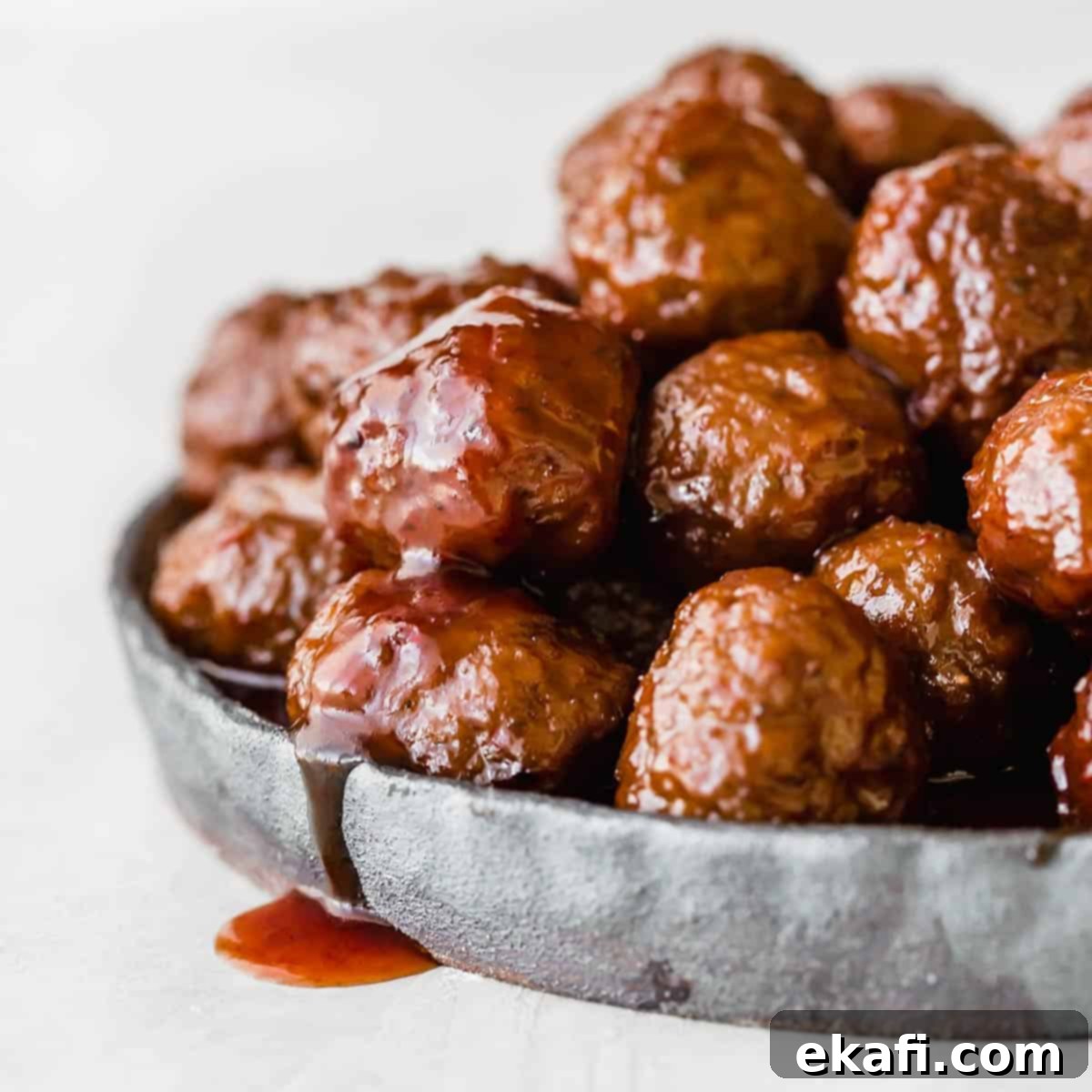 Gridiron Grub 23 Crock pot Grape Jelly Meatballs on a black plate against a white background.