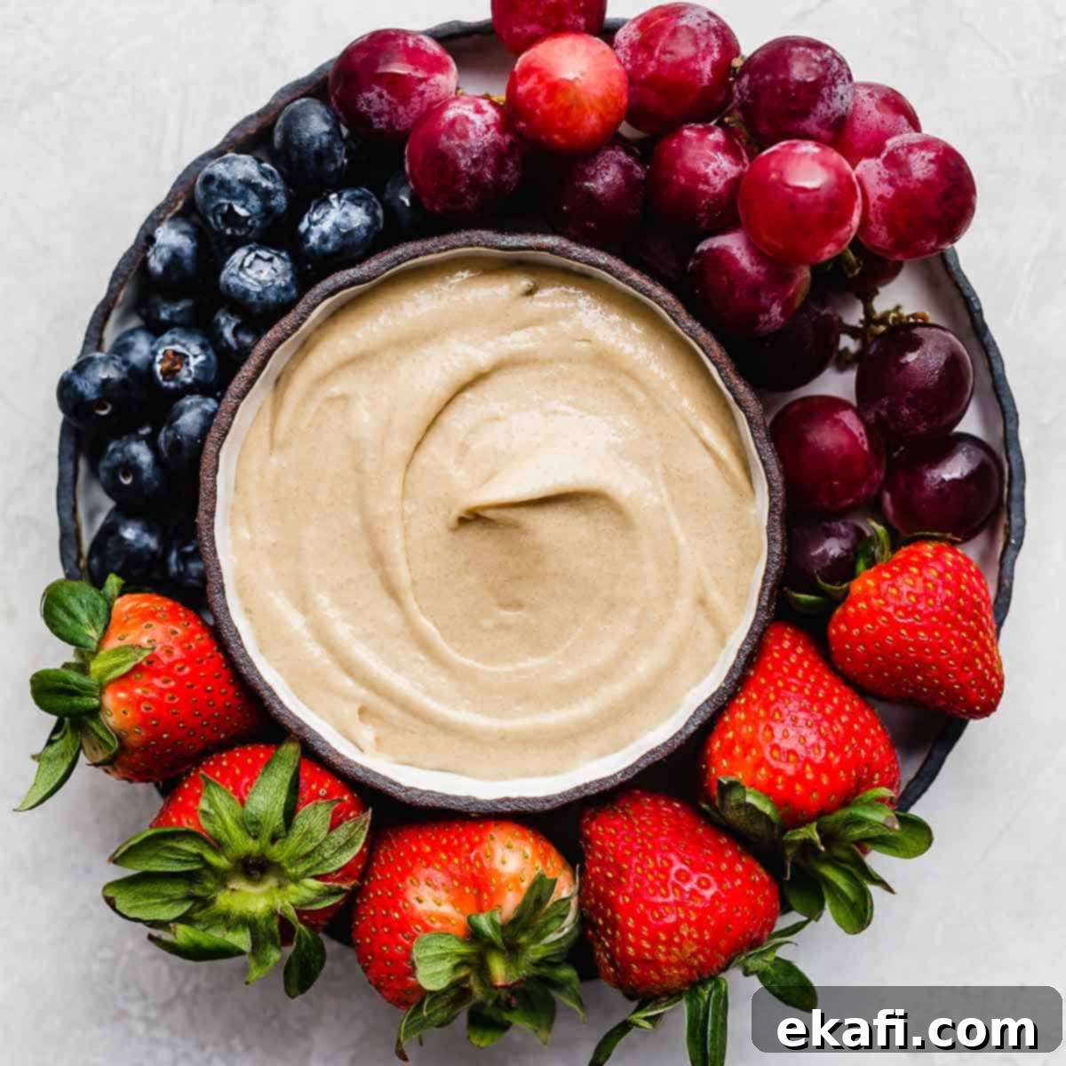 Gridiron Grub 5 Cream Cheese Fruit Dip surrounded by grapes, strawberries, and blueberries.