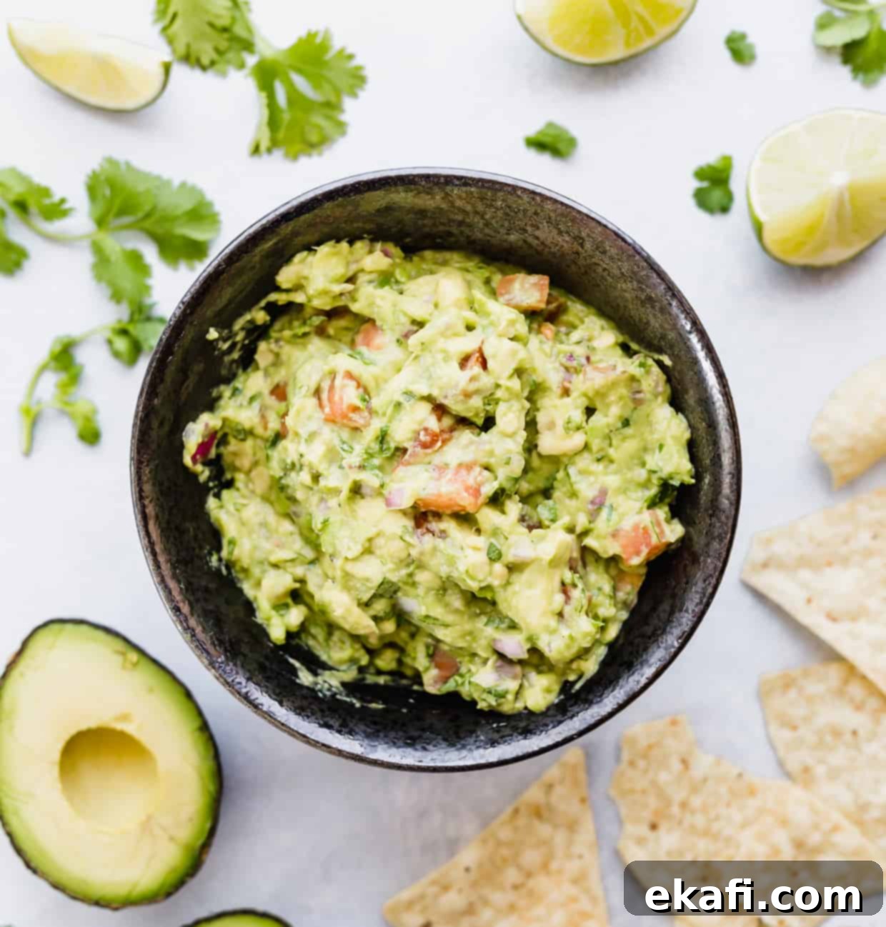 Gridiron Grub 7 Bowl of guacamole surrounded by tortilla chips, cilantro, and limes.