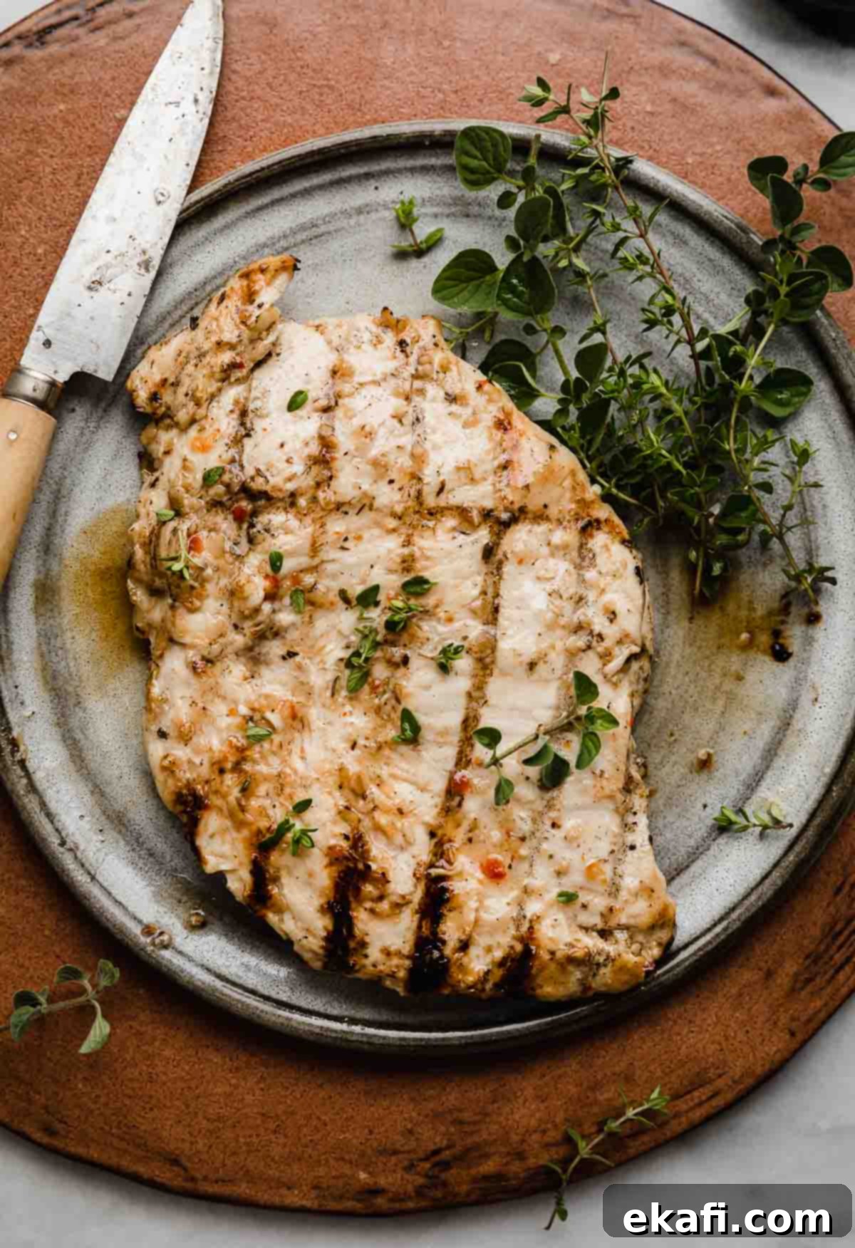 Zesty Italian Grilled Chicken 7 A grilled chicken that was marinated in an Italian chicken marinade, on a gray plate on a brown background.
