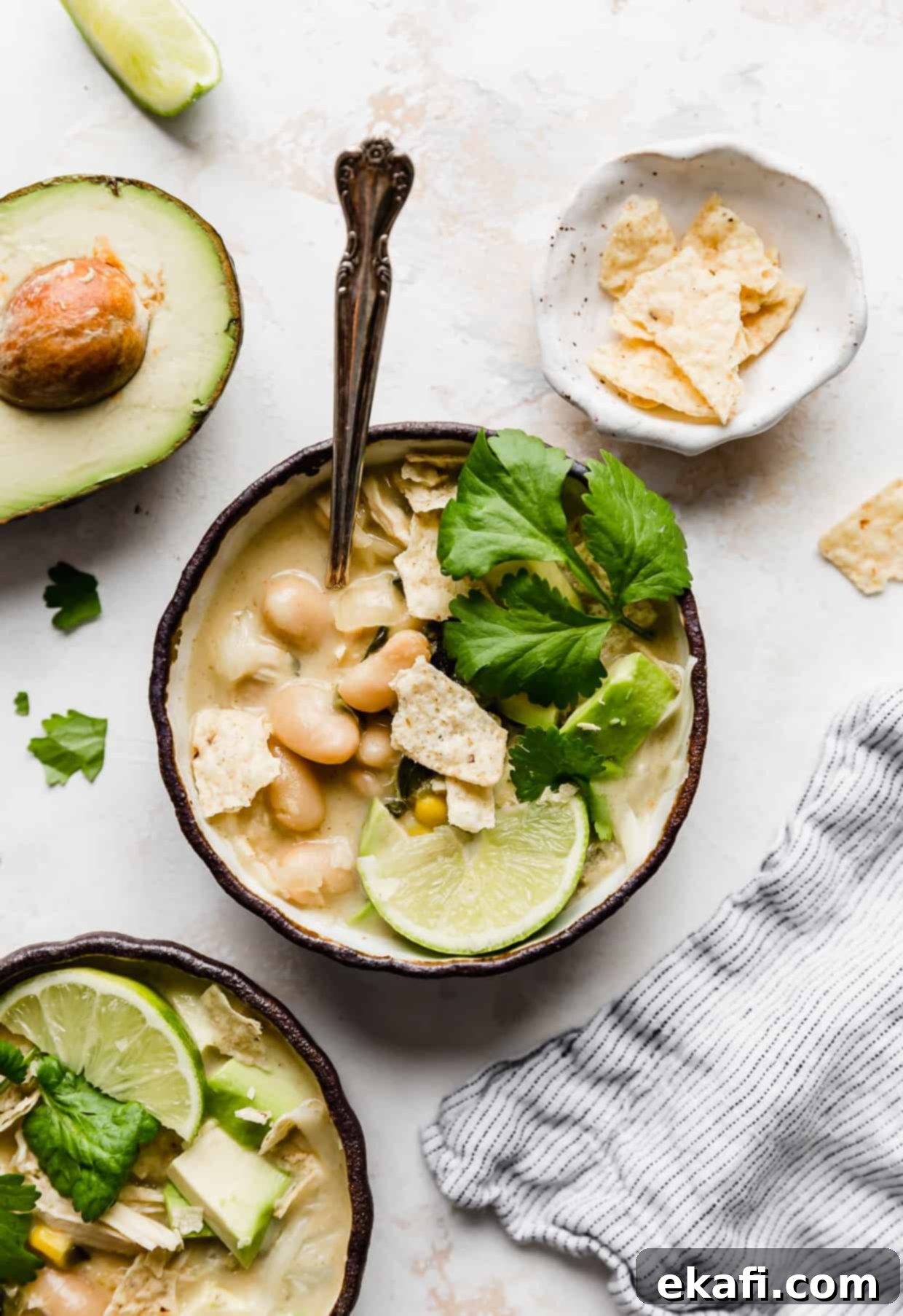 Creamy White Chicken Chili 2 A bowl of white chicken chili topped with cilantro, lime wedge, and crushed tortilla chips, ready to be served.