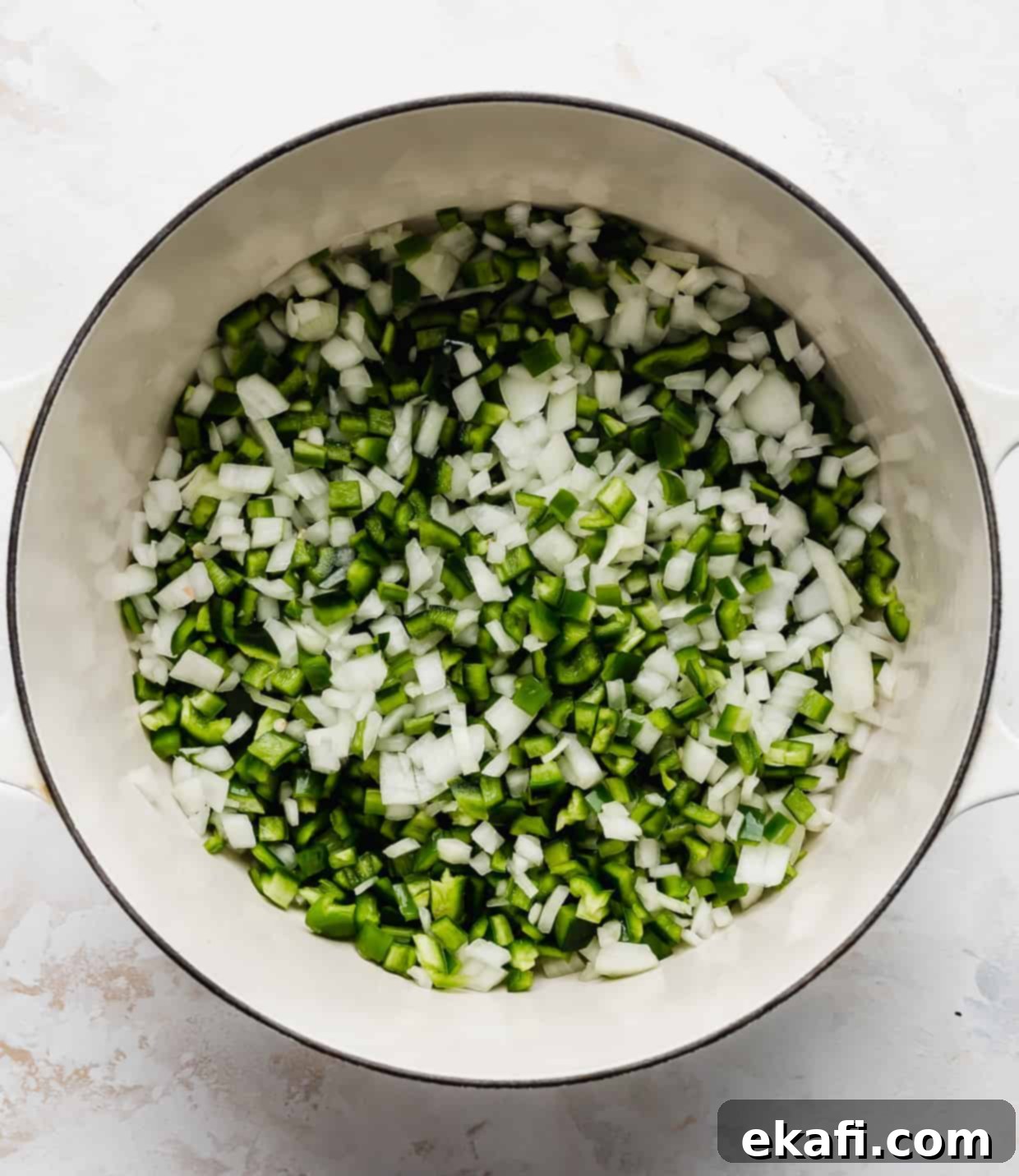 Creamy White Chicken Chili 4 A white pot full of diced onion and diced green peppers, sautéing on the stovetop.