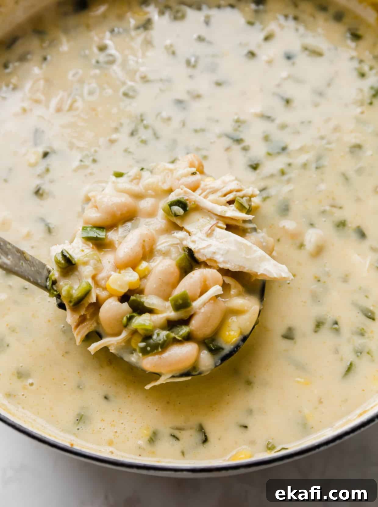 Creamy White Chicken Chili 6 A ladle scooping up creamy Best White Chicken Chili from a large pot.
