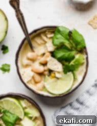Creamy White Chicken Chili 9 A bowl of The Best White Chicken Chili topped with a lime wedge, cilantro, and crushed tortilla chips.