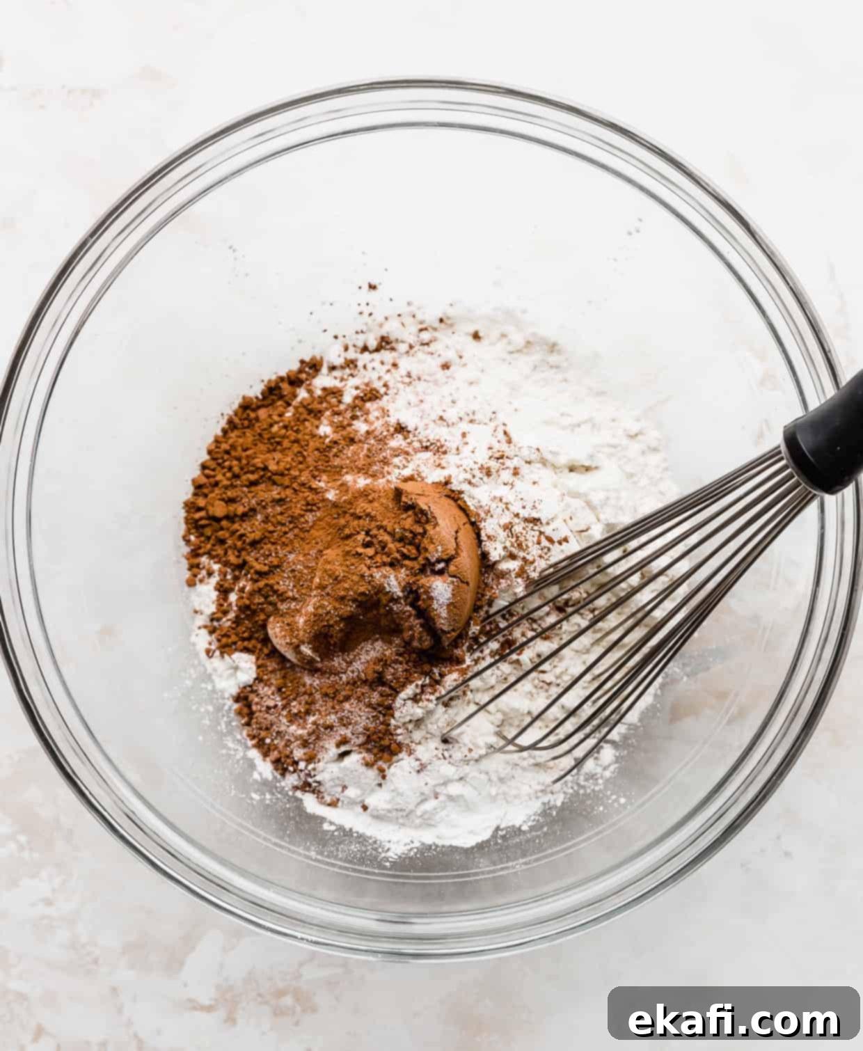Velvet Dream Waffles 5 A glass bowl with dry ingredients in it and a whisk.