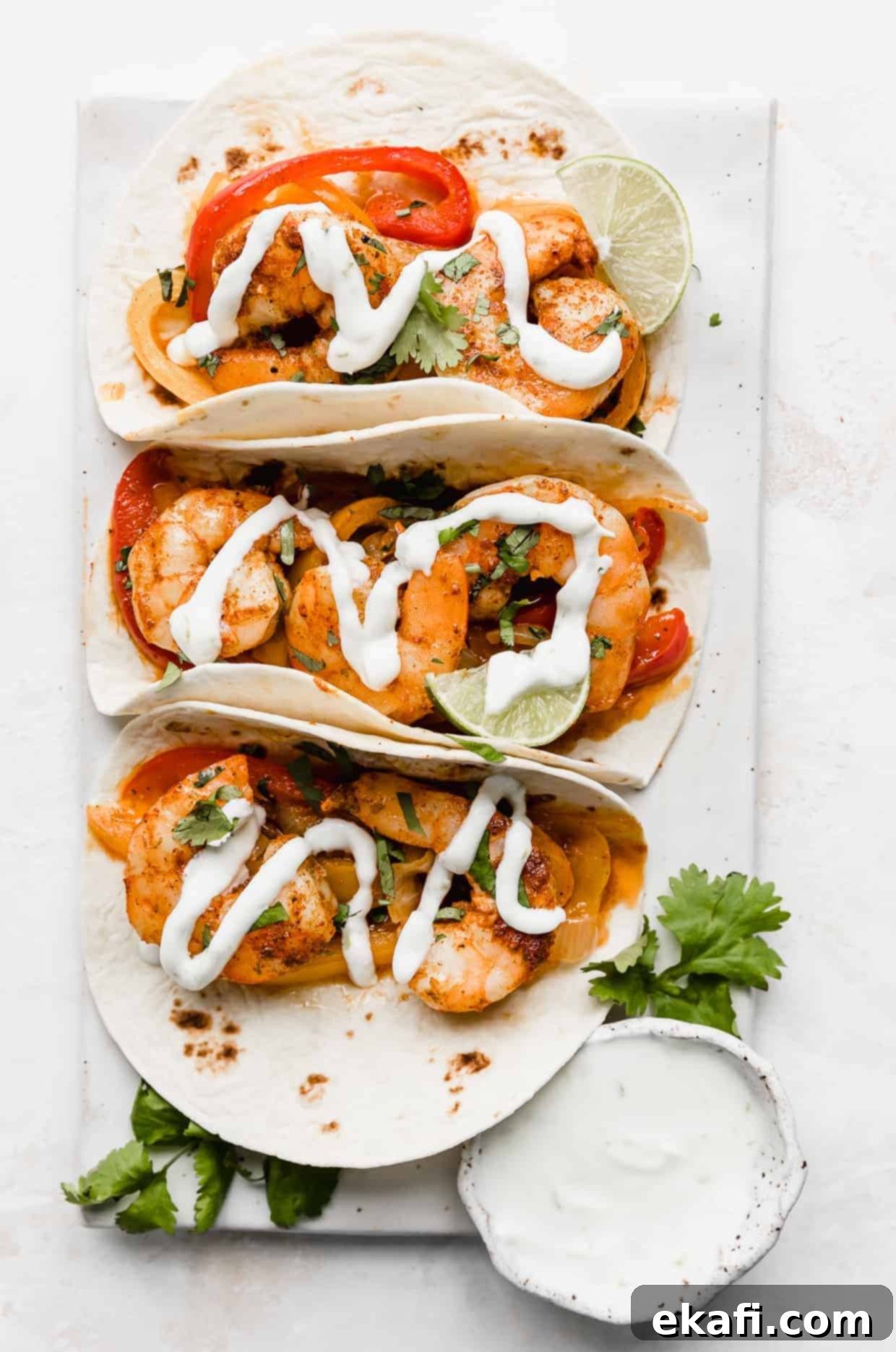 One-Pan Shrimp Fajitas 2 Overhead photo of 3 shrimp fajitas on a white background.