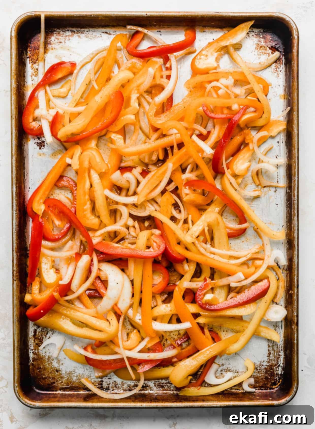 One-Pan Shrimp Fajitas 4 A baking sheet with sliced orange, red, and yellow peppers.