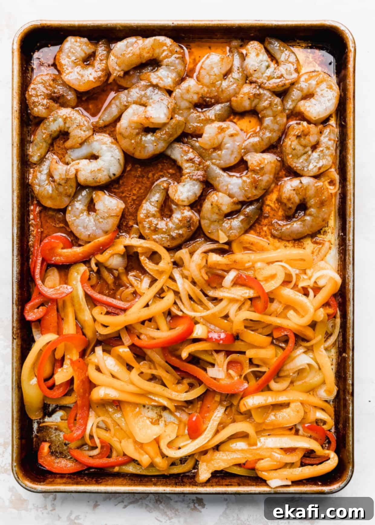 One-Pan Shrimp Fajitas 5 Shrimp and sliced peppers on a baking sheet against a white background.