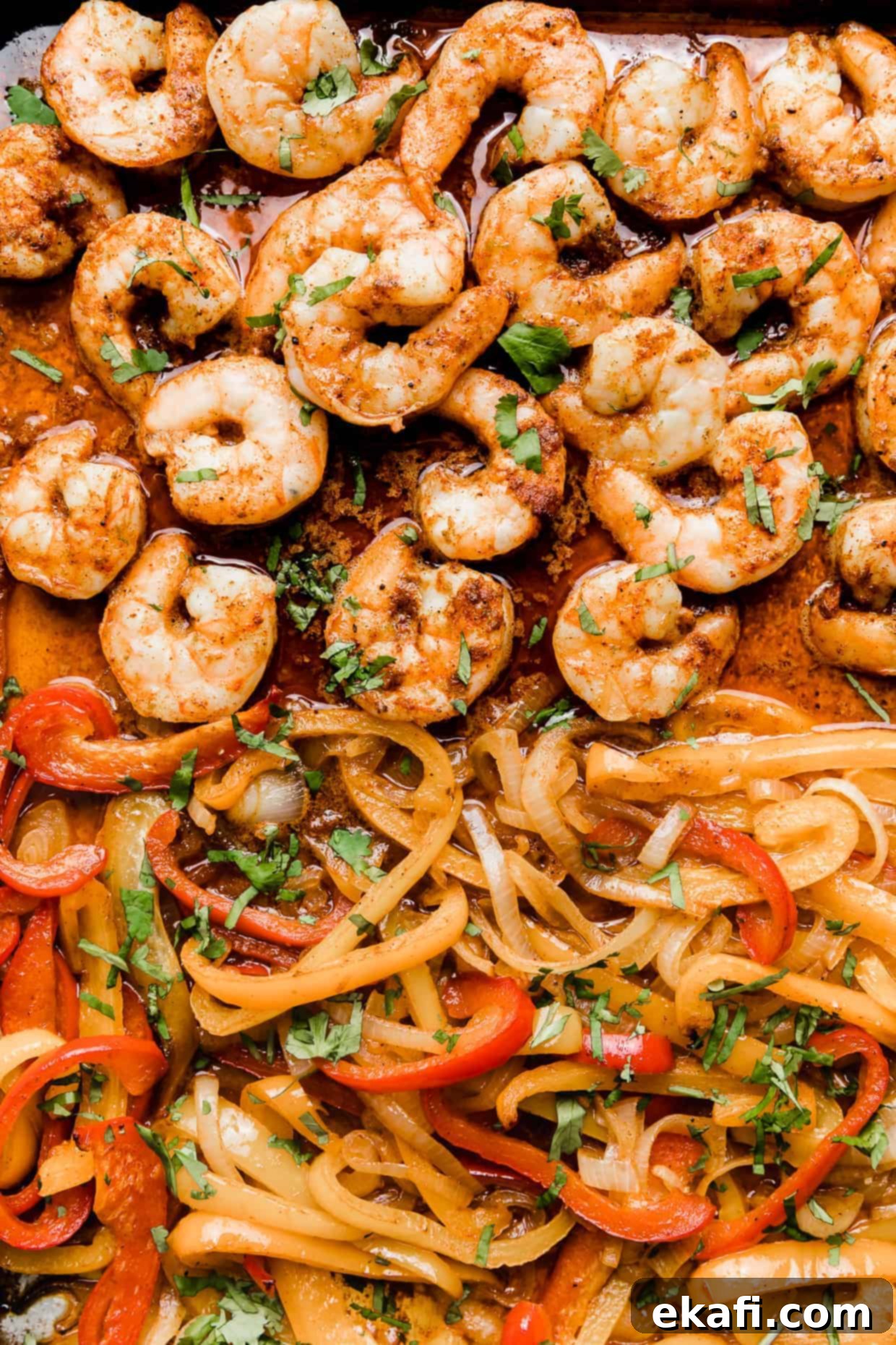 One-Pan Shrimp Fajitas 7 A close up photo of cooked shrimp and cooked sliced red, yellow, and orange peppers.